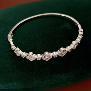 Elegant silver clover bracelet with white zircon inlay on green velvet background