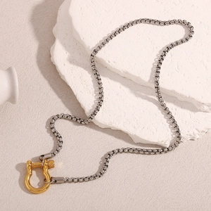 Detail of 18K gold-plated U-shaped horseshoe pendant on a silver-tone chain necklace