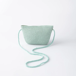 Détail d'un sac en paille tissé main vert clair en forme de trapèze et bandoulière tressée