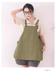 Detail view of military green canvas apron featuring side snap buttons and large front pocket