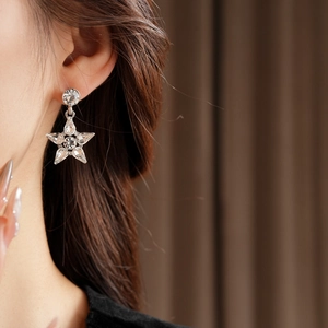 Close-up of star-shaped silver drop earrings with marquise-cut crystals on model