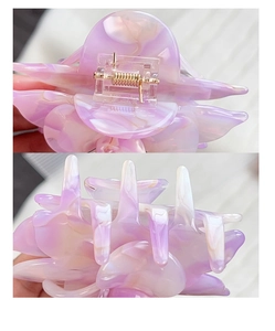 Detailed macro view of acetate floral hair claw with purple marble texture and golden spring