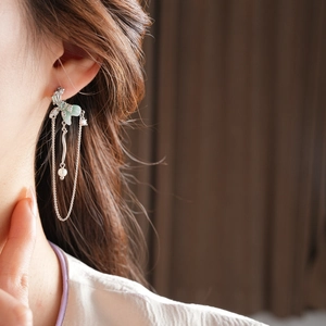 Detailed view of elegant light green flower earrings with long tassels and a white pearl