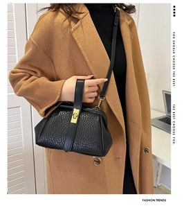 Detail of black faux crocodile leather handbag with gold clasp and detachable shoulder strap