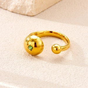 Detailed close-up of a gold-plated open ring featuring a green gemstone on stone background