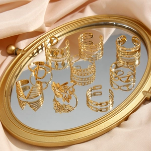 Set of adjustable 18K gold plated stainless steel geometric rings on a mirror tray