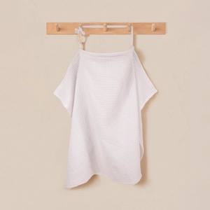 Detail of white cotton waffle nursing cover with wooden ring hanging on a rack
