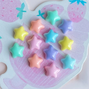 Macro shot of colorful mini resin star charms in pastel macaron tones on a pattern base
