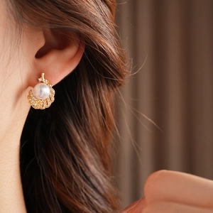 Elegant gold leaf earring with white pearl and diamonds shown on a model's ear