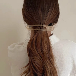 Detailed view of a beige matte shark hair clip worn by a model for an elegant updo hairstyle
