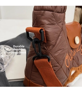Detail of a brown quilted down tote bag with orange strap and reinforced side hooks