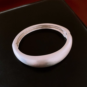 Détail de la finition brossée mate argentée sur le bracelet large avec fermoir