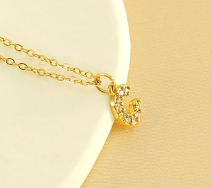 Vue détaillée d'un pendentif G doré serti de zircons sur une chaîne en acier inoxydable