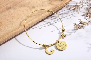 Detail of adjustable gold stainless steel bracelet with celestial moon and star charms