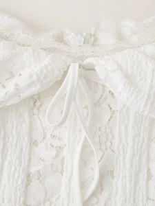Détail de l'encolure d'une robe en dentelle blanche avec nœud élégant et texture fine