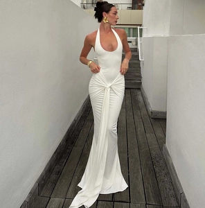 Full view of white halter neck maxi dress with waist tie on elegant wooden hallway