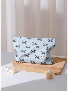 Blue cotton makeup bag with black bow patterns on a wooden tray with a lifestyle setting