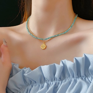 Gros plan du collier double avec perles bleues et pendentif étoile sur modèle