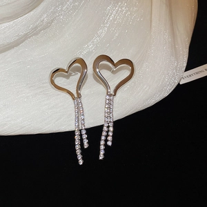 Detailed close-up of silver heart fringe earrings with cubic zirconia on white silk