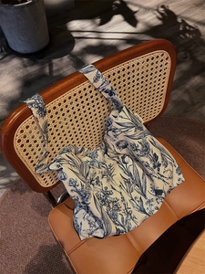 Detailed view of canvas tote bag with vintage blue floral patterns hanging on a rattan chair