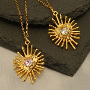 Vue macro du collier avec pendentif cœur étoilé doré et zircone rose sur pierre noire