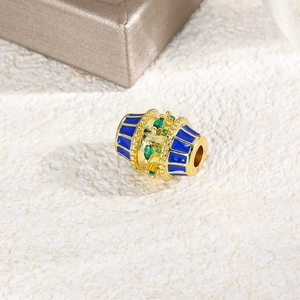 Macro shot of oval gold bead with blue enamel and green zircon for DIY jewelry making