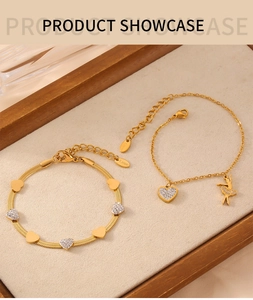 Detail of gold titanium steel bracelets set with heart and ballerina charms with zircons