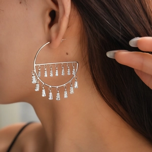 Close-up of silver geometric hoop earrings with sparkling zircon fringe on a model