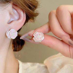 Close-up of pink flower stud earrings with a pearl center on a female model