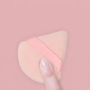 Piumino da trucco triangolare rosa con nastro, mostra una consistenza molto elastica