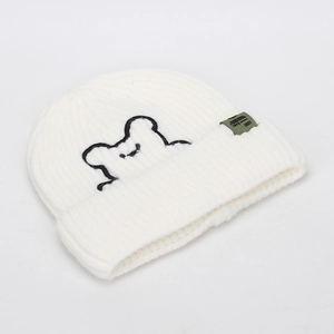 Detail of white beanie with cartoon bear embroidery and olive green woven side label