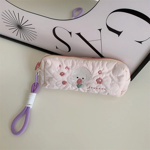 Detail of pink quilted pencil case showing delicate cartoon dog and flower embroidery