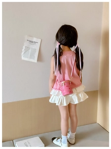 Pink bucket bag with cherry print and gold chain strap worn by a little girl