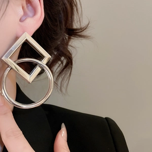 Detail of silver geometric earrings with interlocking square and round polished metal frames