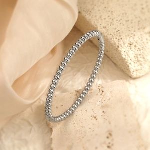 Elegant 18K gold-plated minimalist beaded bangle on champagne silk and sandstone