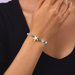 Close-up of starfish bead bracelet with white pearls and blue accents on a wrist