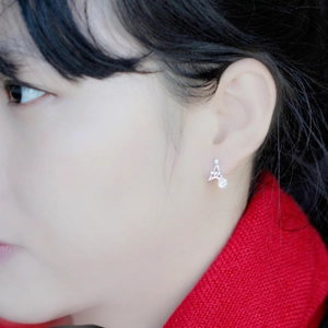 Close-up of a silver Eiffel Tower stud earring with a sparkling zircon on the earlobe