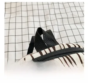 Detail of comfortable black webbing handle and smooth metal zipper on zebra print backpack