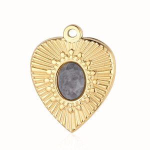Macro detail of a vintage gold-plated heart pendant with a gray faceted gemstone inlay