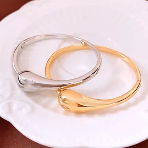 Polished gold and silver water drop cuff bracelets set in a minimalist luxury style