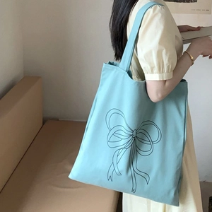 Detail einer hellblauen Canvas-Tasche mit schwarzem minimalistischem Schleifendruck am Träger