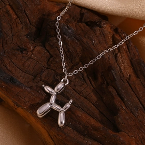 Detailed view of balloon dog pendant with mirror finish on dark rustic wood texture
