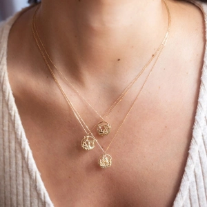 Detailed layered gold necklace showing Eiffel Tower and Arc de Triomphe round pendants