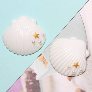 Close-up of white resin seashells with gold stars and pearls for DIY crafts