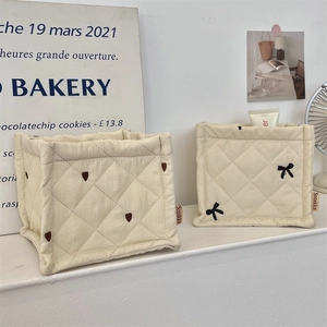 Detalle de cestas de almacenaje acolchadas crema con bordados de corazones y lazos negros