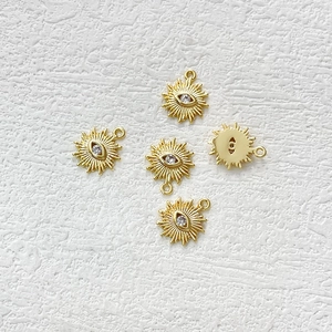 Detailed macro view showing five 14k gold plated evil eye sunburst charms with zircon