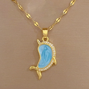 Detail of a luxury gold-plated necklace with a blue enamel dolphin pendant and clear zircons
