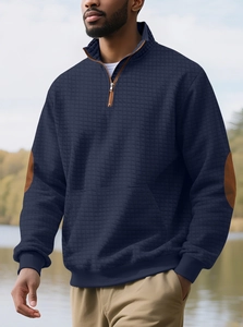 Detail eines dunkelblauen Waffelstrick-Pullovers mit braunen Ellenbogen-Patches