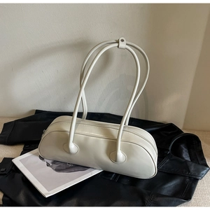 Detail of a minimalist cream white cylindrical handbag with slim shoulder straps on a leather jacket