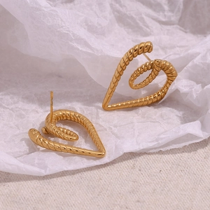 Detail of gold heart stud earrings with twisted rope texture on textured background